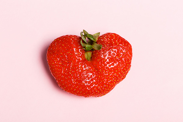 Bizarre Misshapen Strawberry on Pink Background