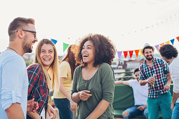 Young adults laughing as they enjoy each other’s company at an outdoor event with colourful bunting.