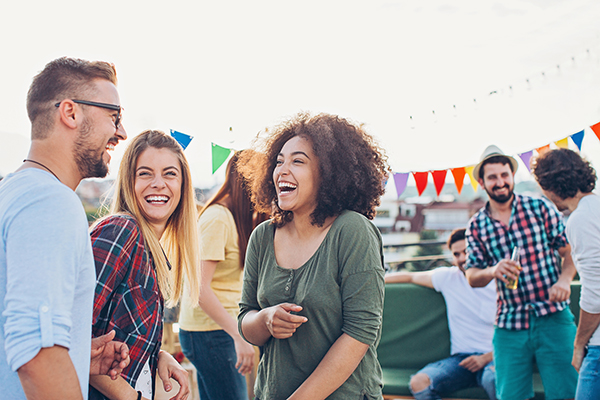 De jeunes adultes rient en bonne compagnie lors d’une activité extérieure avec des banderoles colorées.