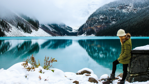 Une femme se tient près du lac Louise dans le parc national de Banff (Alberta) en hiver.