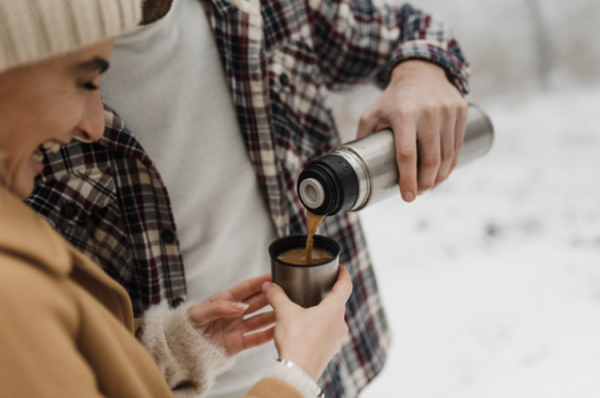 A man pours a hot chocolate beverage into a cup for a woman.