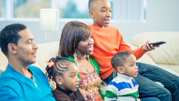 A family with a mother, a father, and their three children are watching television.