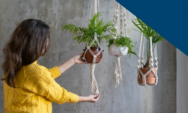 Une femme crée des porte-plantes de style macramé.