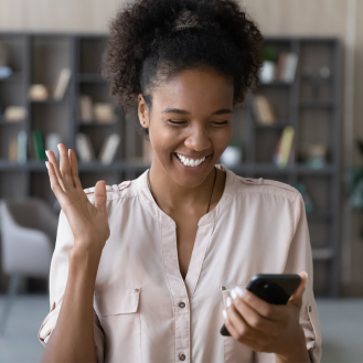 Femme qui regarde son téléphone cellulaire avec une expression heureuse et excitée.