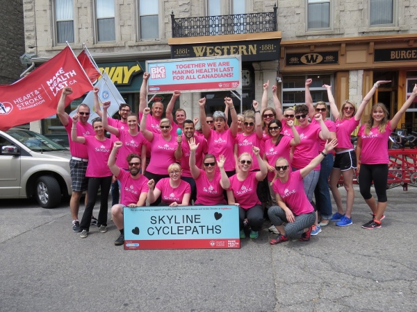 Image of Skyline Cyclepaths team in downtown Guelph. Team members raise their arms with a fist in celebration of their achievement.